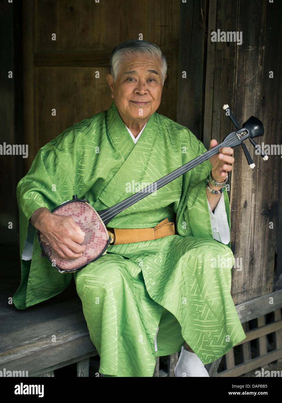 Elderly Okinawan man playing sanshin at Ryukyu Mura, historical village ...