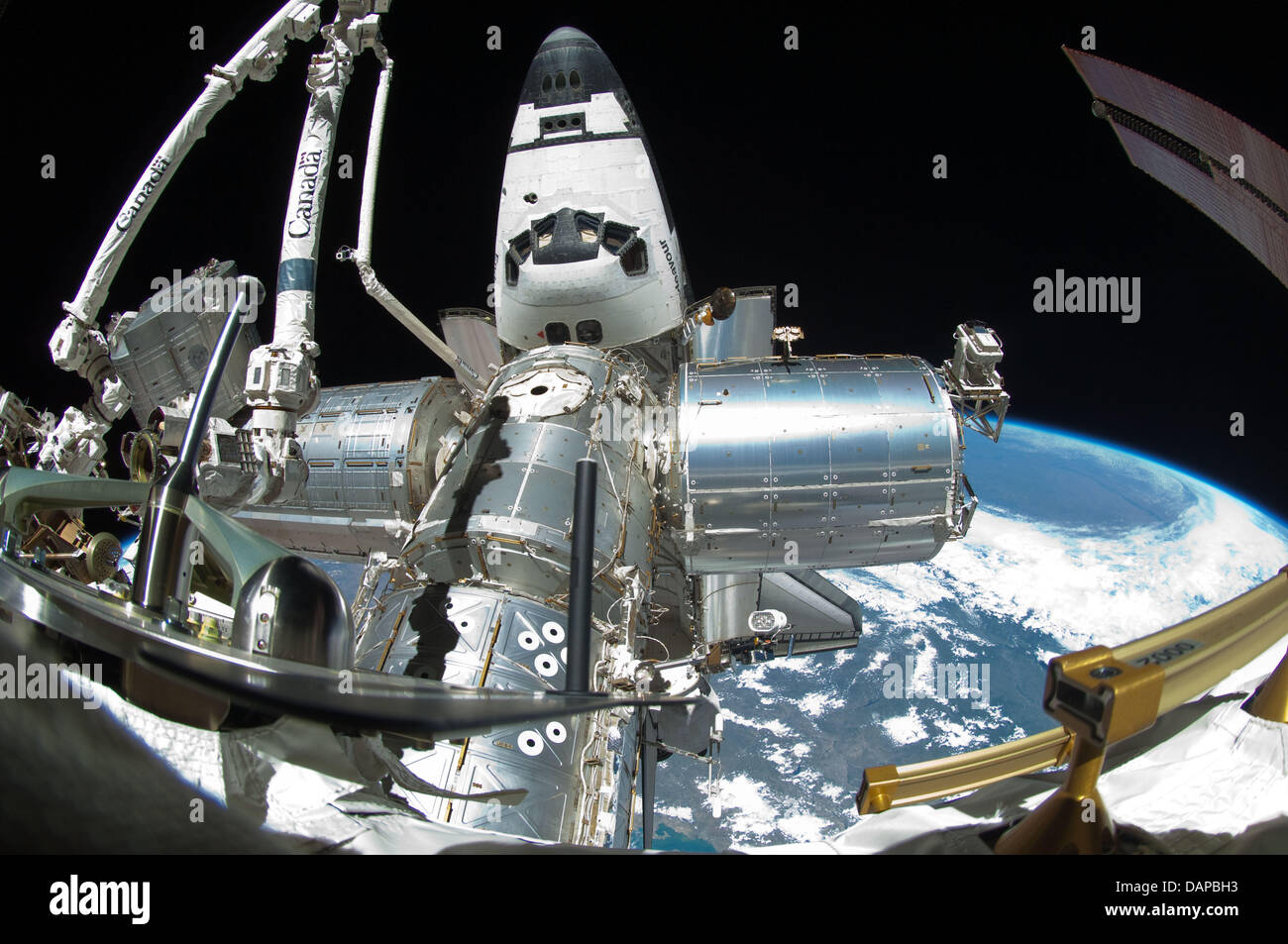 A portion of the International Space Station and the docked space shuttle Endeavour is featured in this image photographed by a spacewalker, using a fish-eye lens attached to an electronic still camera, during the STS-134 mission's fourth session of extravehicular activity (EVA) on May 27, 2011. The blackness of space and Earth's horizon provide the backdrop for the scene. Credit:  Stock Photo