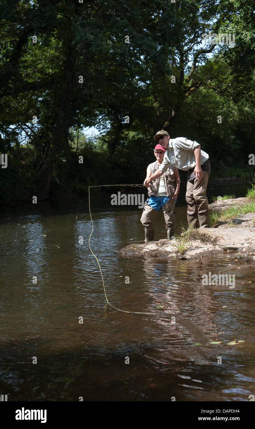 Fly fishing a gillie instructing a pupil on the scenic River Lyd Devon