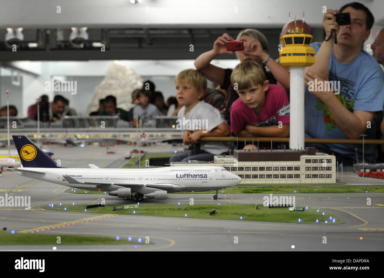 Visitors look at 'Knuffingen' airport at the model railway Miniatur Wunderland in Hamburg, Germany, 12 August 2011. Miniatur Wunderland is celebrating its 10 year anniversary on Tuesday. Since its opening on 16 August 2001, around 8.3 million visitors have come to see the world's largest model railway. Photo: CHRISTIAN CHARISIUS Stock Photo