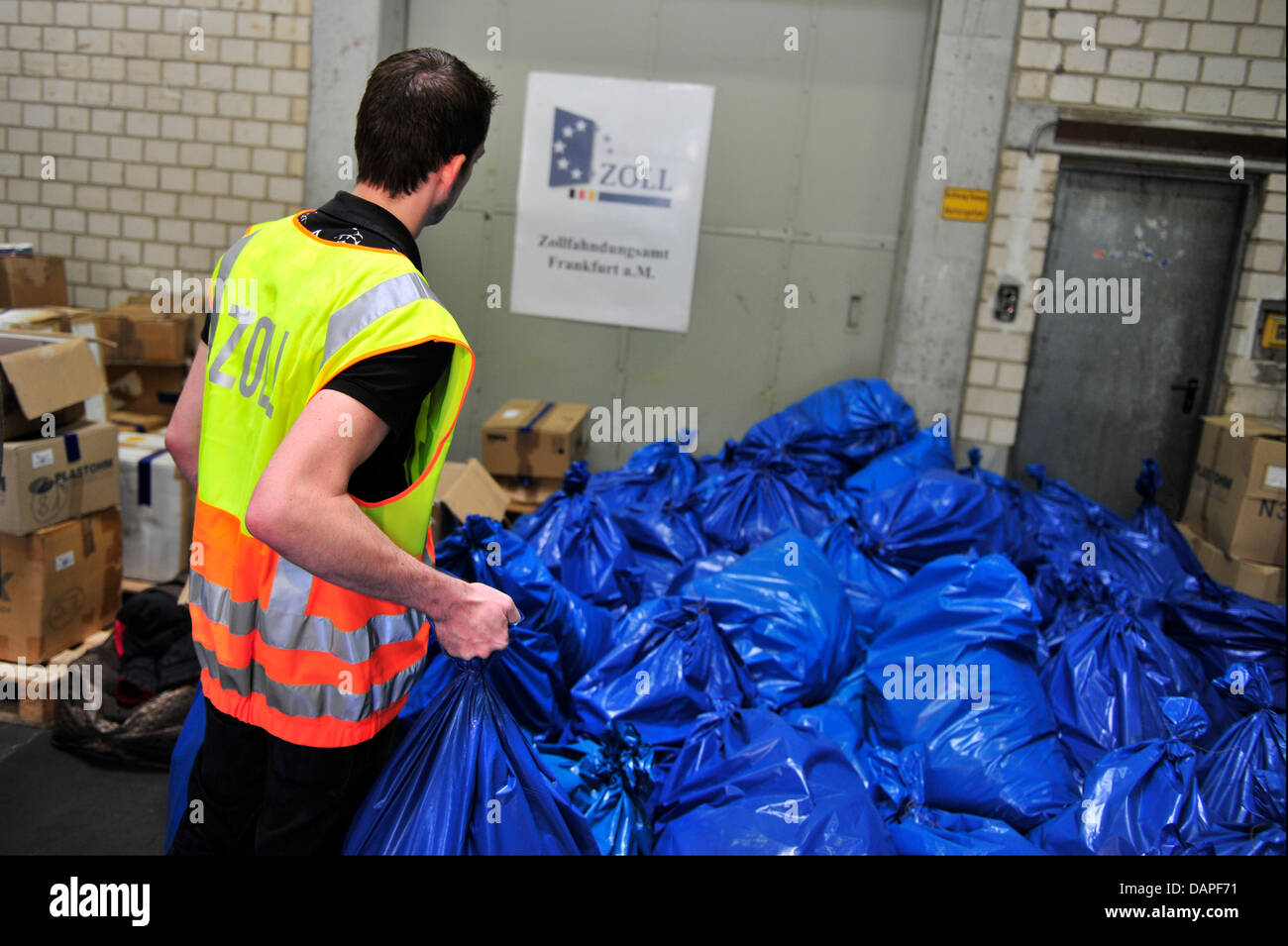 An employee of the German customs lifts a blue bag filled with confiscated potency pills at a storage room at the Rhein-Main-Gebiet in Germany, 17 August 2011. More than five million units of anabolica and other doping agents, 250 000 potency pills and 50 000 agents for weight loss, as well as 20 000 fake brand-name clothes were brought from the storage faciclity to a waste inciner Stock Photo