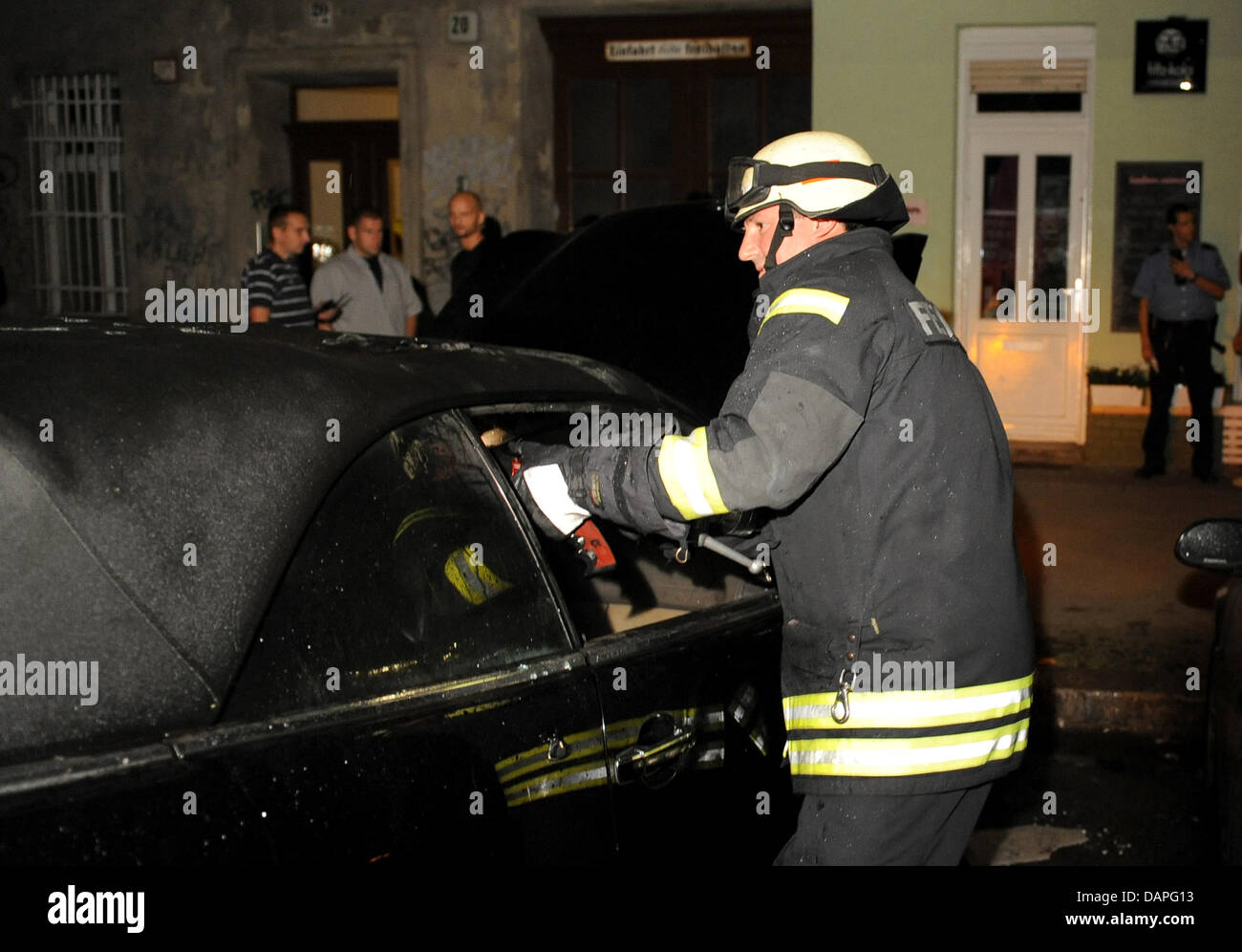 A fireman puts out the flames from a burning car in Berlin, Germany, 18 August 2011. Overnight, cars in several districts of Berlin were set on fire. The series of arson has reached a peak point with the fires of that night. According to the police, eleven cars were set on fire and another one was damaged. Photo: Britta Pedersen Stock Photo