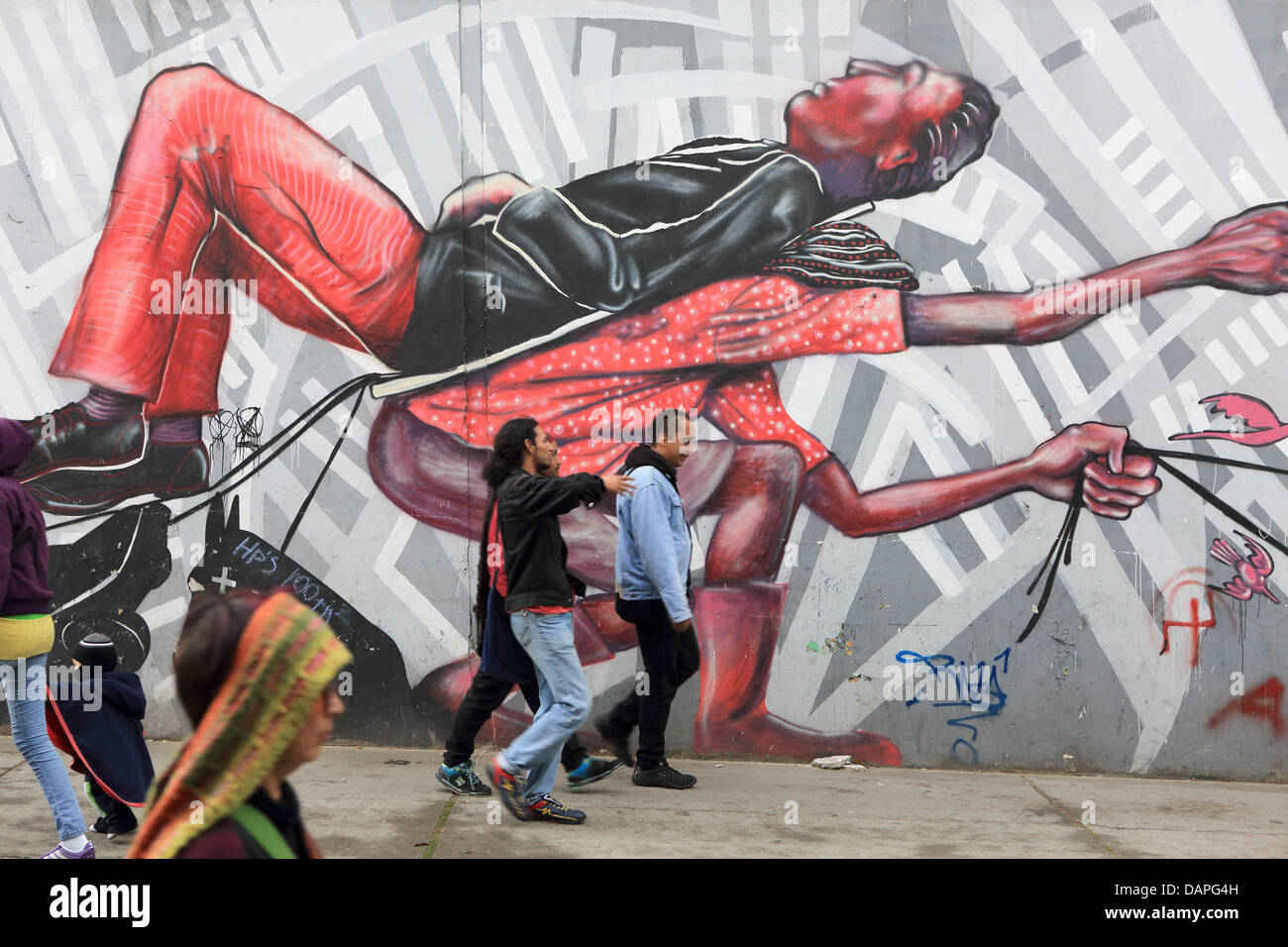 Pedestrians walking past street art graffiti mural in La Candelaria barrio of Bogota, Colombia. Stock Photo