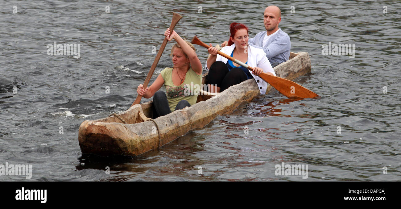 Students Julia Ender, Franziska Hentze and Tobias Hilsenitz (FRONT to BACK) row inside a replica of a prehistorical dugout through city port in Greifswald, Germany, 19 August 2011. On the weekend of 20 and 21 August 2011, the students want to row from Greifswald to Stralsund in an unusual experimental-archaeological project. In June 2011, the students used Stione Age tools to build Stock Photo