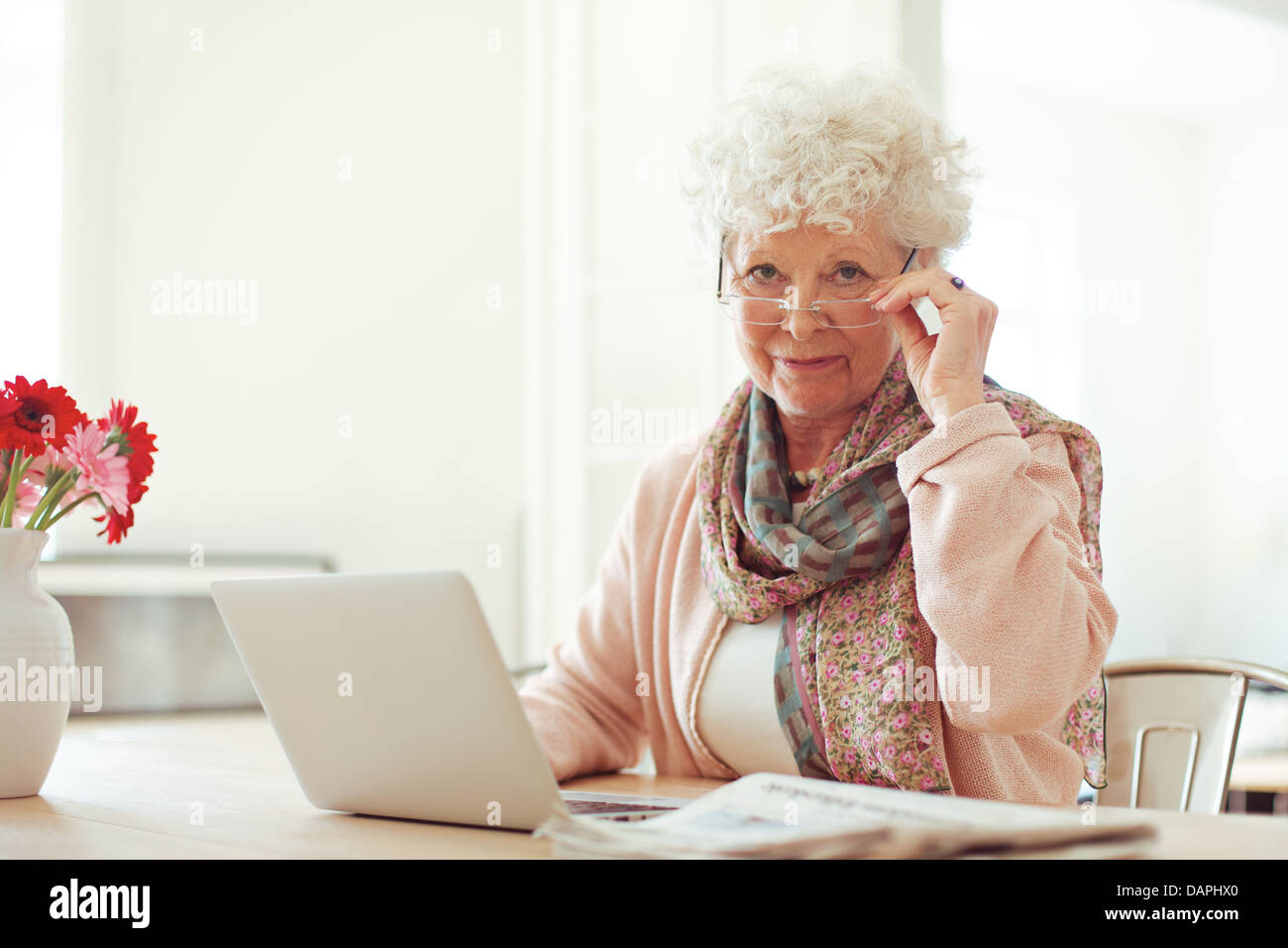 Stylish senior woman at home with laptop looking at you Stock Photo