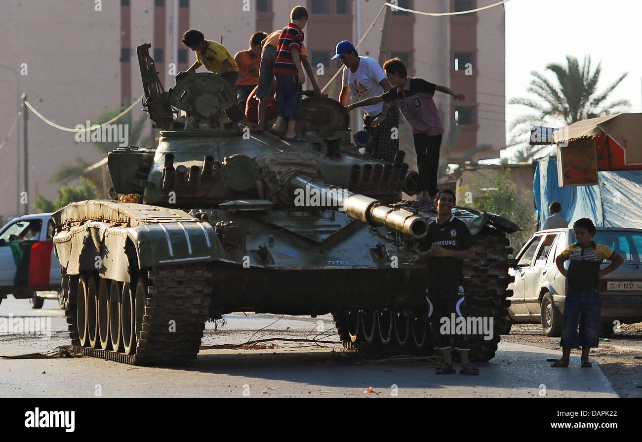 Kinder spielen am Mittwoch (24.08.2011) auf einem zerschossenen Panzer in al Sawija, Libyen, rund 50 Kilometer westlich der Hauptstadt Tripolis. Das Regime des libyschen Diktators Gaddafi ist am Ende, doch trotz der Siegesfeiern der Rebellen kämpfen seine letzten Getreuen erbittert gegen den Untergang. In Tripolis und anderen Orten Libyens lieferten sich Aufständische und Gaddafis  Stock Photo