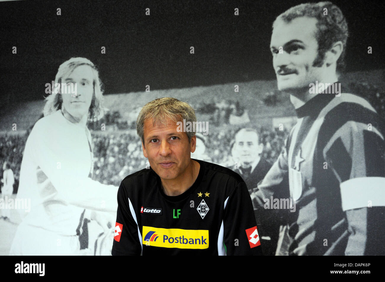 Lucien Favre, coach of German Bundesliga team Borussia Moechengladbach, stands in front of a poster of the former players Guenter Netzer (L) from Gladbach and Sandro Mazzola from Inter Milan during an interview at the head office in Moenchengladbach, Germany, 24 August 2011. In an interview with the German Press Agency dpa Favre signaled that he is not very interested in the curren Stock Photo