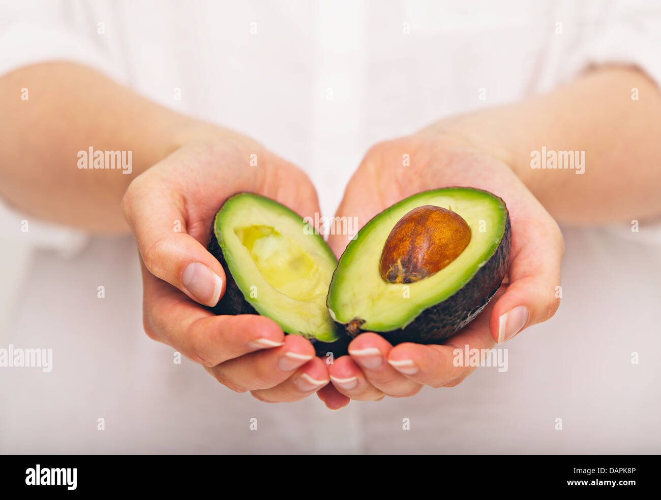 Female hand holding sliced avocado Stock Photo