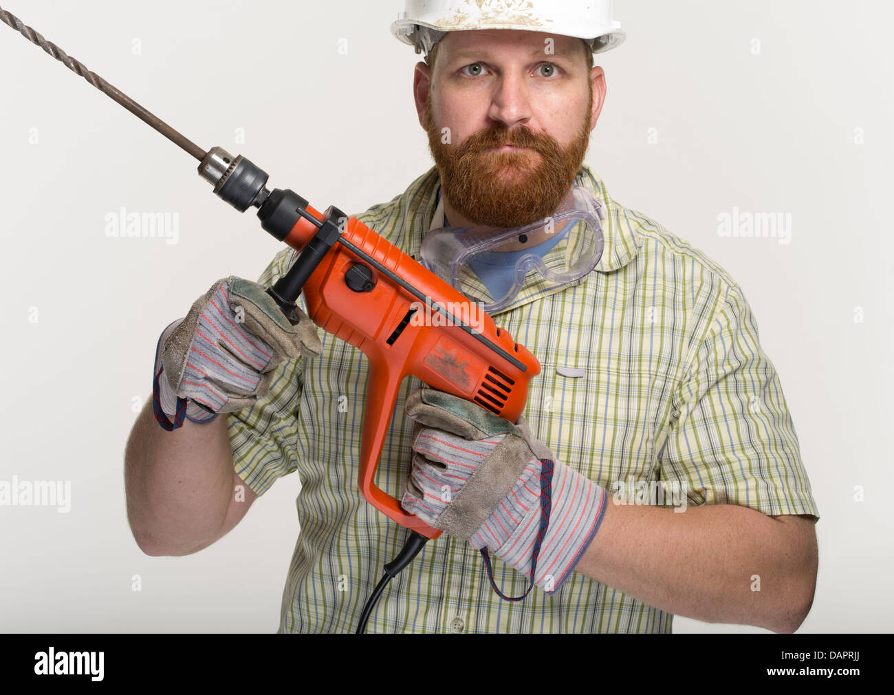 Workman with electric power  impact drill and larger concrete drill bit. Stock Photo
