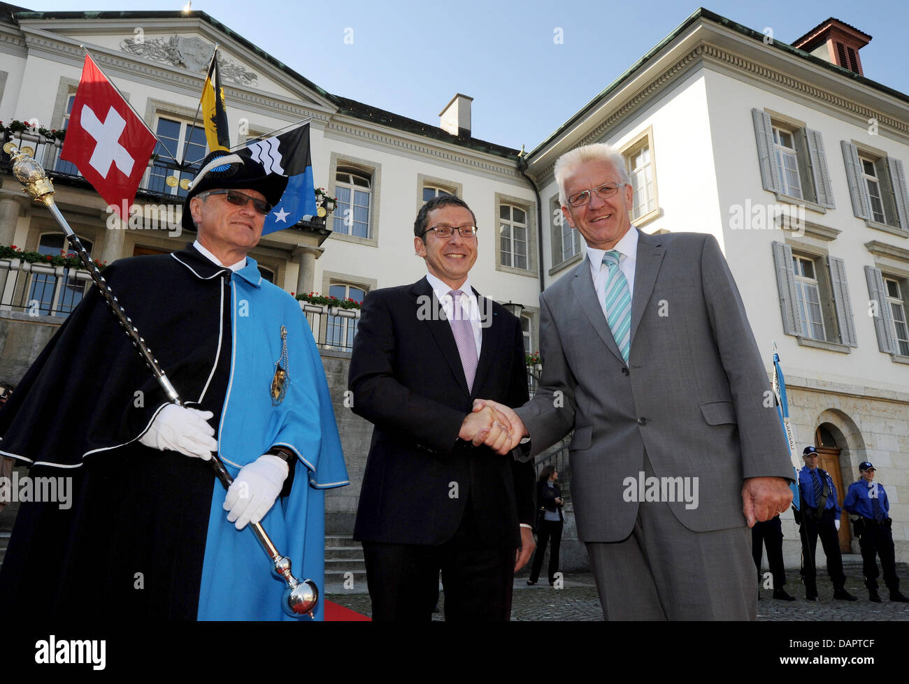 Governor of Aargau, Urs Hofmann (M), and Premier of Baden-Wuerttemberg Winfried Kretschmann (R) shake hands next to a so-called 'Weibel' in front of the cantonal government building in Aarau, Switzerland, 31 August 2011. In Aarau, Kretschmann was welcomed by the cantonal government to discuss the economic cooperation, questions of citizens' initiatives and cooperations in the healt Stock Photo