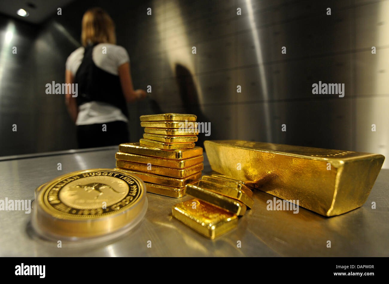 ILLUSTRATION - A staff member of the private coin and precious metal dealer pro  aurum opens a safe while gold bars and coins are seen in the front in  Munich, Germany, 31