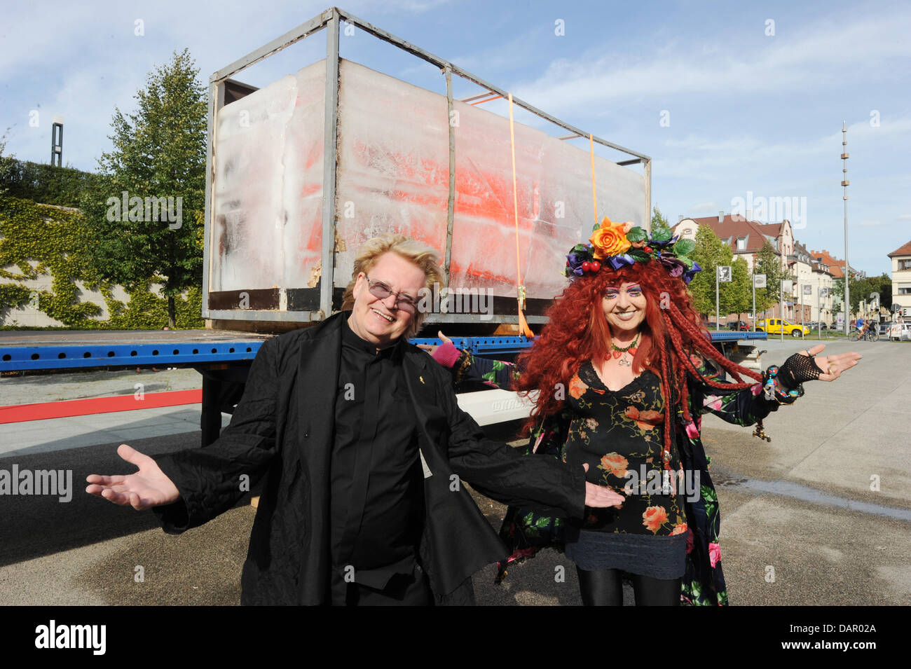 Action artist HA Scult stands with his muse Elke Koska in front of A Ford Fiesta frozen in a block of ice in front of the Center for Art and Media (ZKM) in Karlsruhe, Germany, 06 September 2011. It is a work by the action artist HA Schult. The car will slowly thaw in the next few weeks for the purposes of the ZKM exhibition 'Car Culture'. The car from a Mannheim company was frozen  Stock Photo