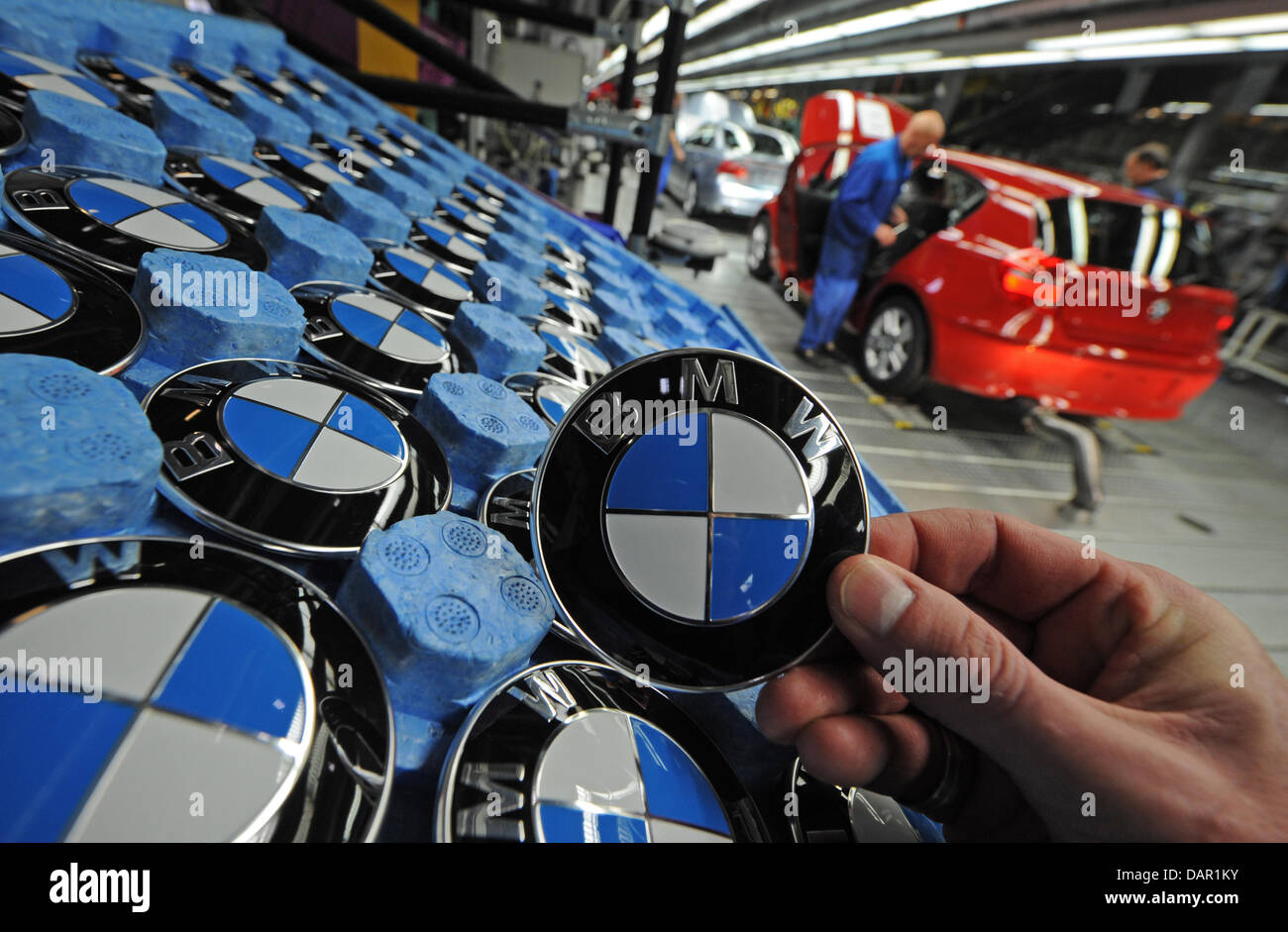 (FILE) An archive photo dated 08 November 2010 shows an employee holding up a BMW emblem in a factory in Regensburg, Germany. BMW continues its record-breaking performance. In August 2011 the car manufacturer from Munich sold 110891 cars and managed to set a new record for the month. Compared to August 2010 deliveries were up 7.4 per cent BMW announced 09 September 2011. Stock Photo