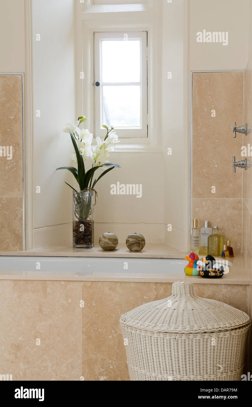 White wicker basket beside stone tiled bath in Ampney Park, 17th