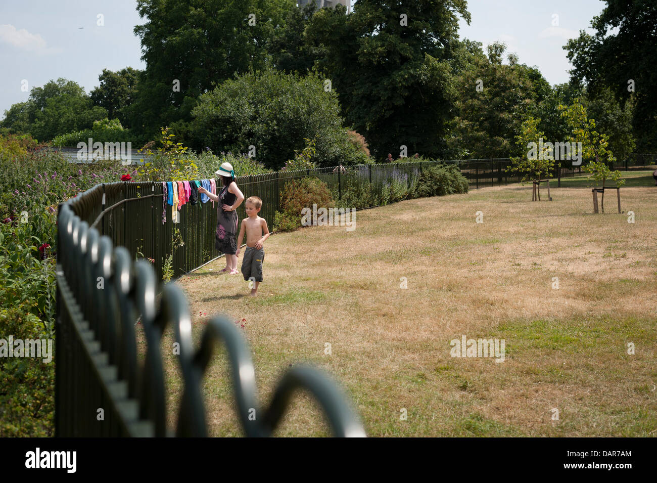 London, UK. 17th July 2013. A woman and a boy hand up their washing to dry in Hyde Park London. As the heatwave continues in the UK, Londoners and tourists alike find ways to cool off. Credit:  Lee Thomas/Alamy Live News Stock Photo