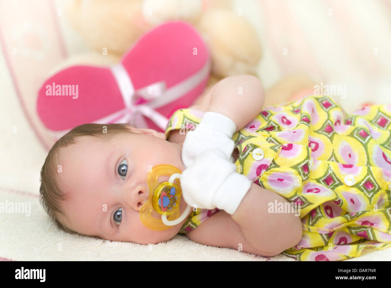 Infant baby girl (1 month old) lying on bed with teddy bear Stock Photo