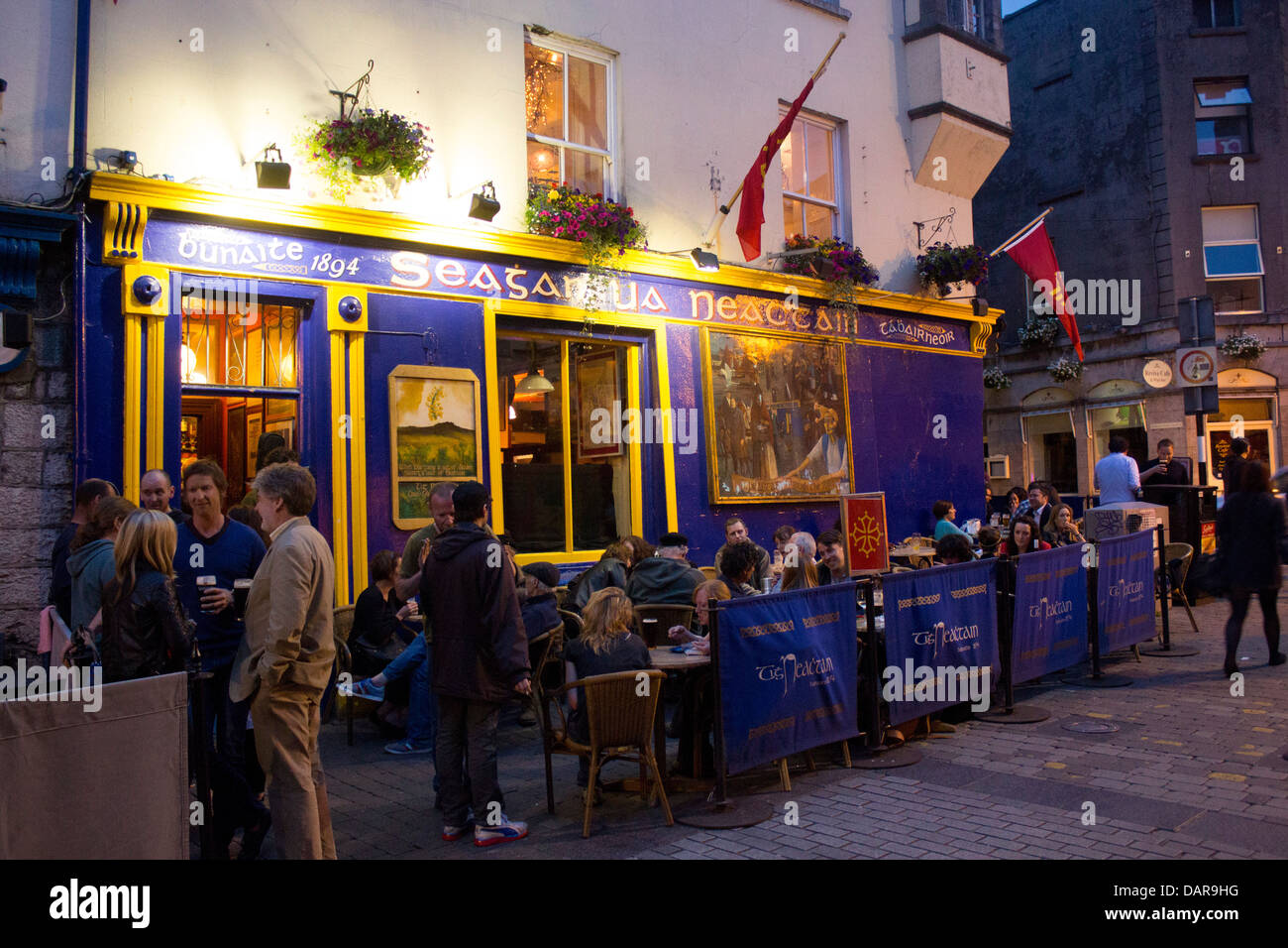 Seatan Ua Neachtain O'Naughton's Bar with people outside drinking and chatting at night Quay Street Galway Republic of Ireland Stock Photo