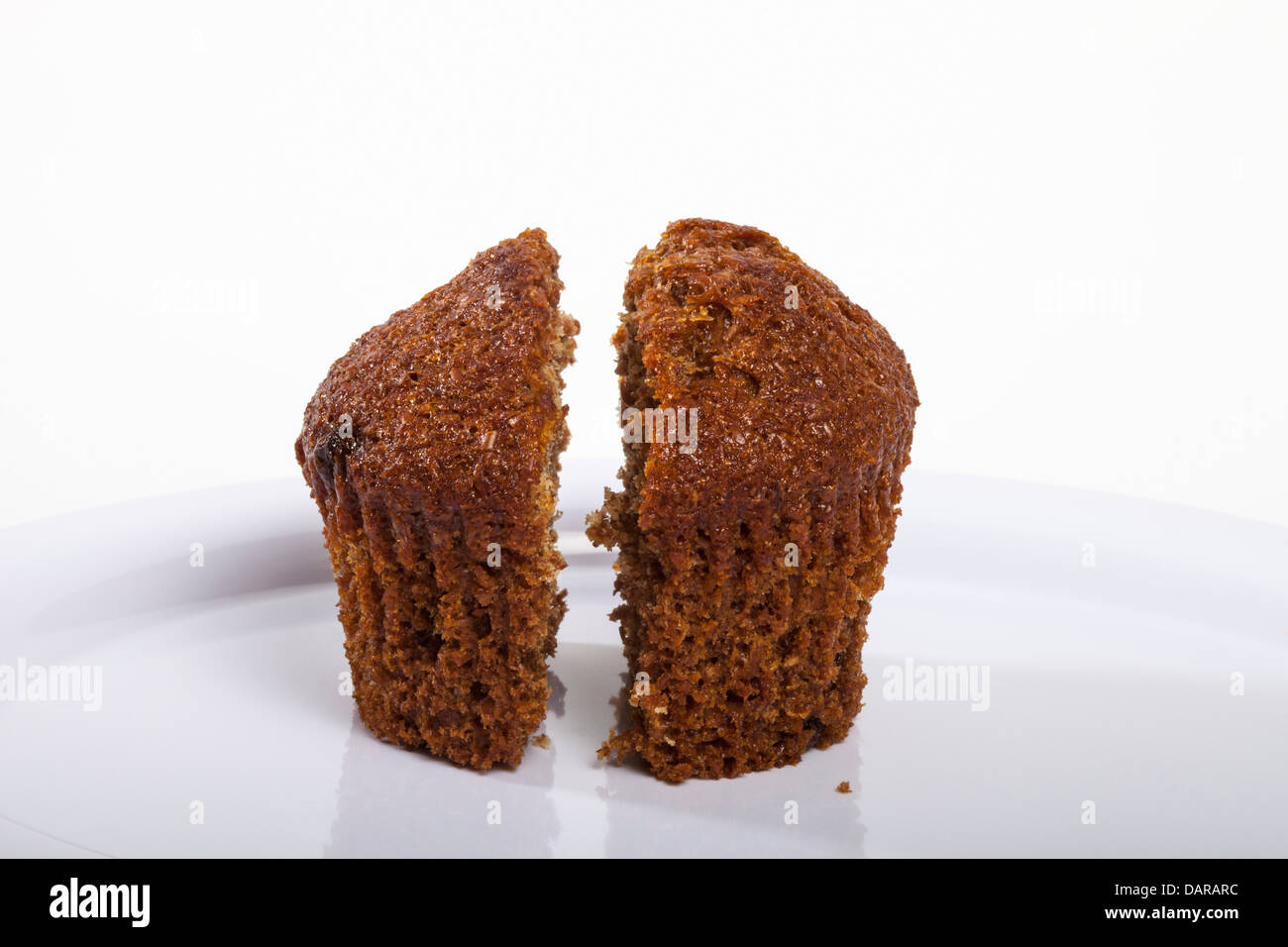 Two halves of a healthy bran muffin on a white plate in the studio Stock Photo