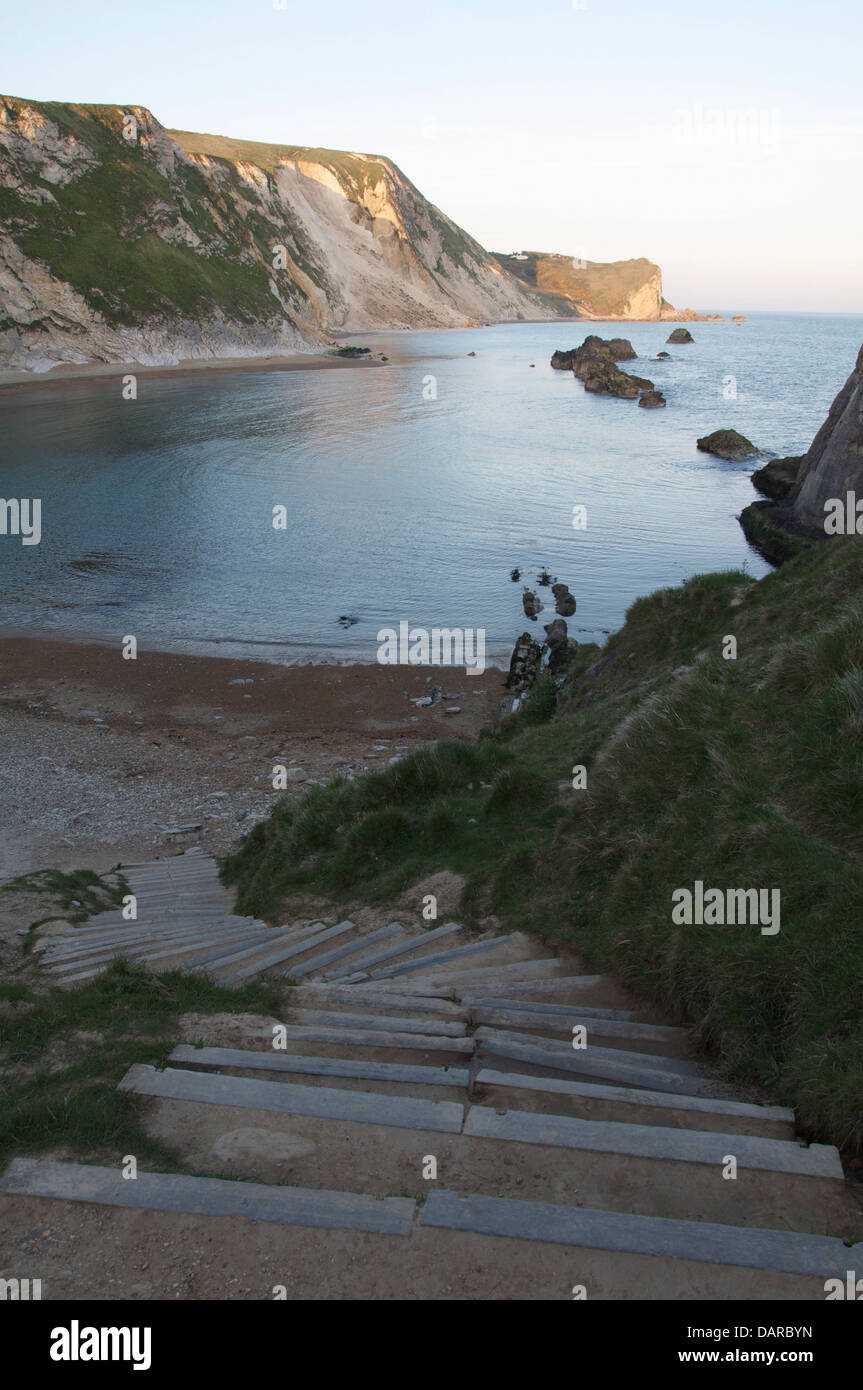 Steps descend to the beach at St Oswald’s Bay on the Jurassic Coast. In the distance are chalk cliffs and the scree of a recent landslide. Dorset, UK. Stock Photo