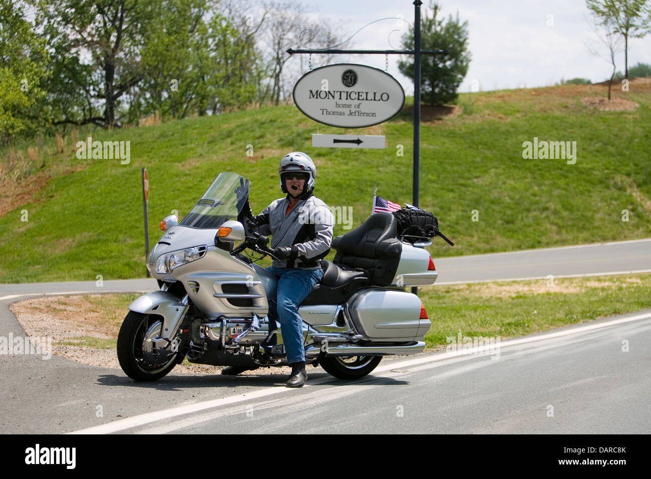 An adult male on a Honda Goldwing motorcycle gestures in front of a sign for Monticello, Charlottesville, Virginia. Stock Photo