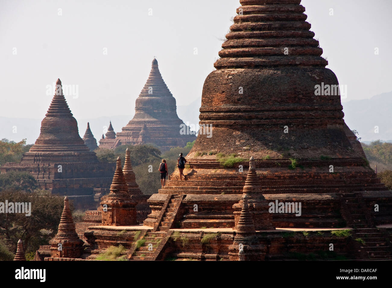 Climbing tourists exploring Buddhist pagodas on Bagan Plains. Stock Photo