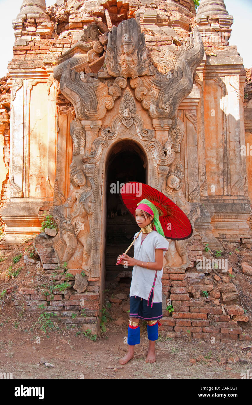 Young Padaung girl with carved doorway of ancient stupa in ruins near Indein village on Inle Lake, Shan State, Myanmar. Stock Photo