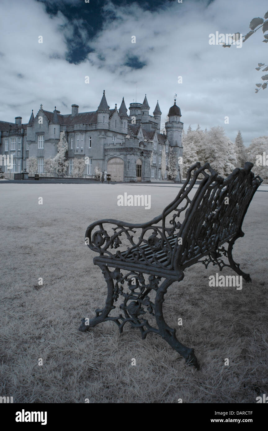 Vertical, infrared image of Balmoral Castle taken from gardens with wrought iron bench in foreground Stock Photo