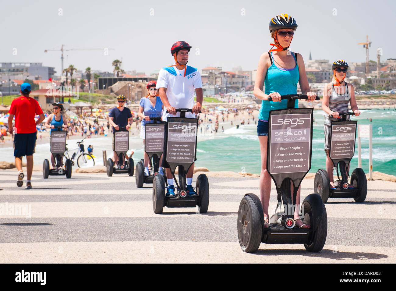 Israel Tel Aviv view to Jaffa Yafo old city over beach bay sea sand promenade tourists riding Segs Segway Electric Scooters Stock Photo