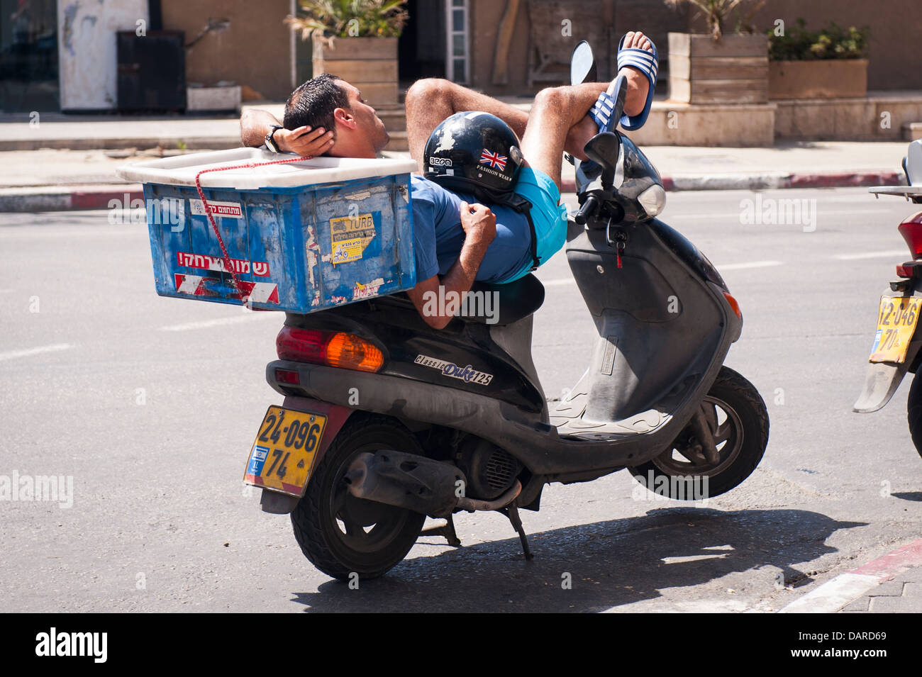 Israel Jaffa Yafo pizza delivery boy man balanced lying in sun on Classic Duke 125 scooter moped motor bike bicycle cycle Stock Photo