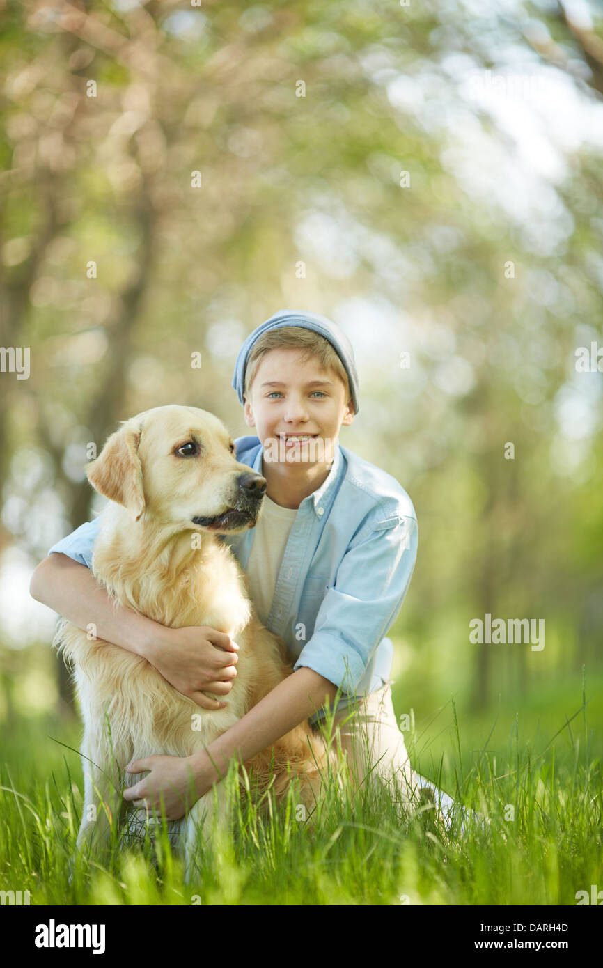 Portrait of cute lad embracing his white Labrador Stock Photo