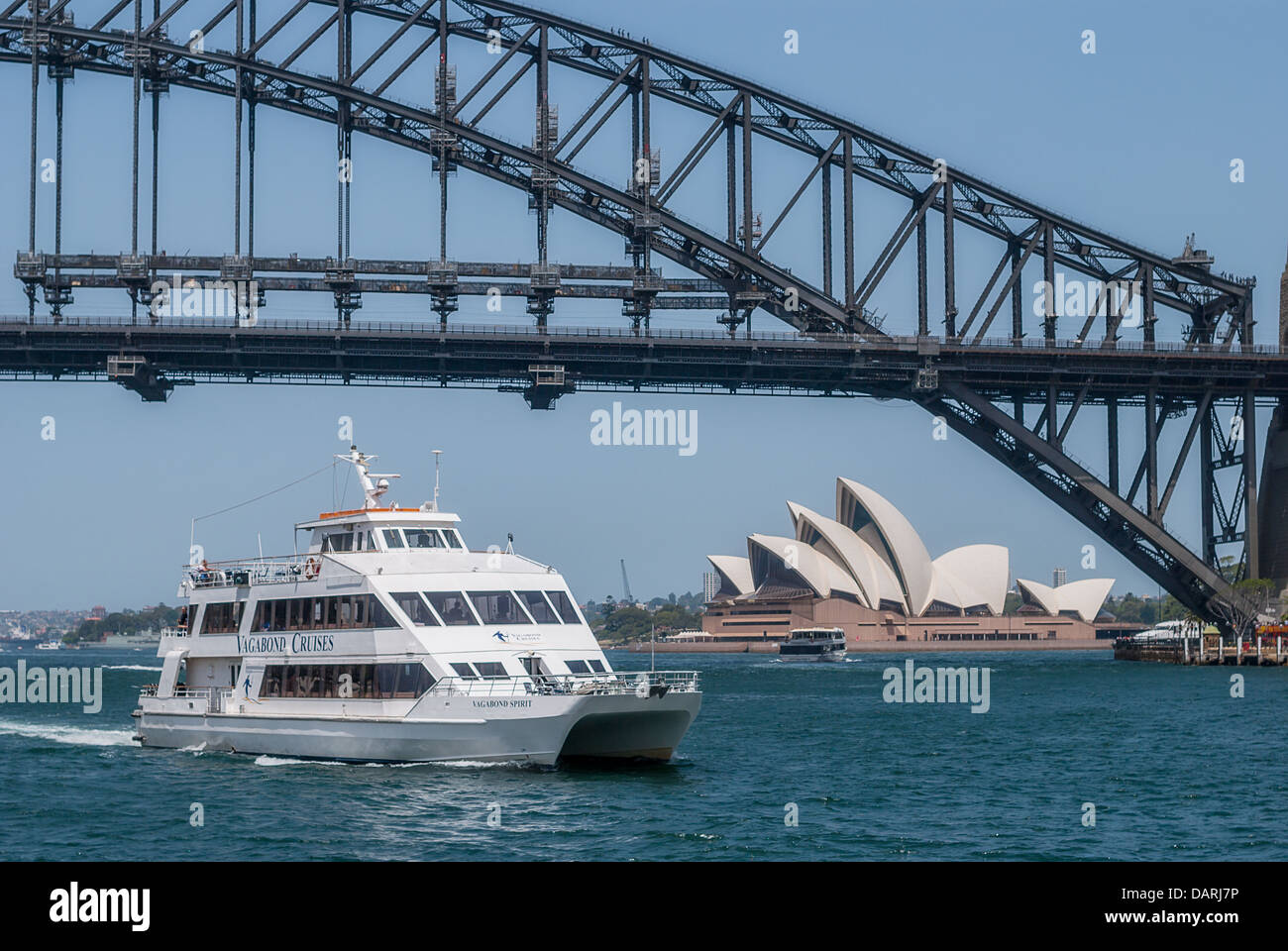 A sightseeing boat takes tourists past the iconic Sydney Harbour Bridge and Opera House. Stock Photo