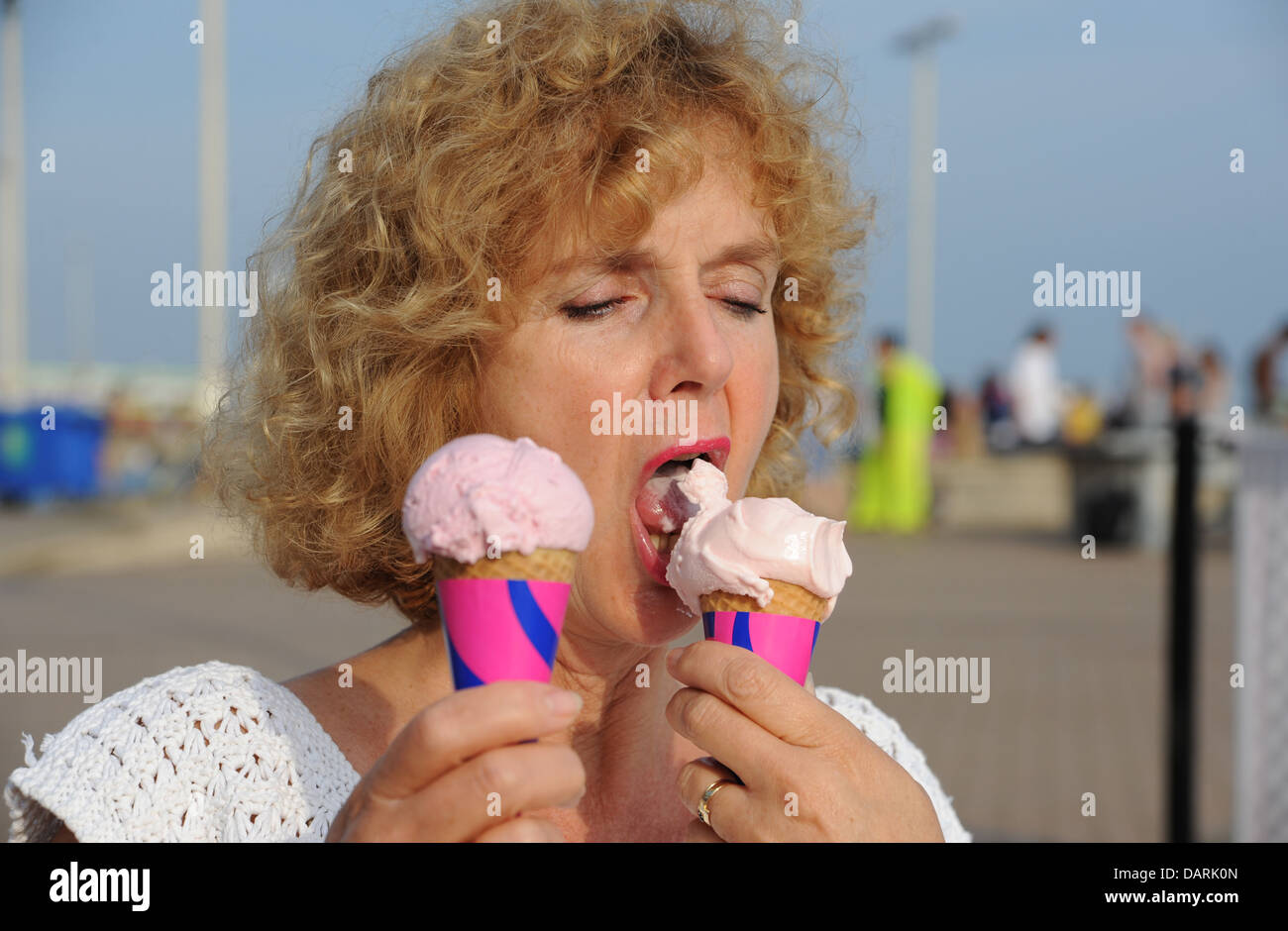 Mature middle aged woman 50s eating ice cream cones in hot weather Stock Photo