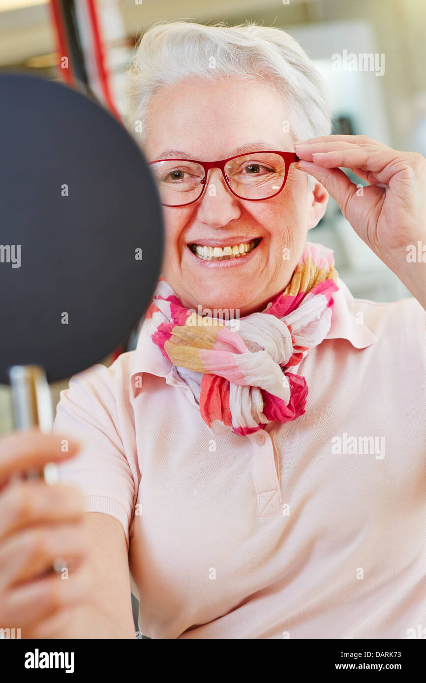 Nearsighted senior woman with new glasses looking into mirror at