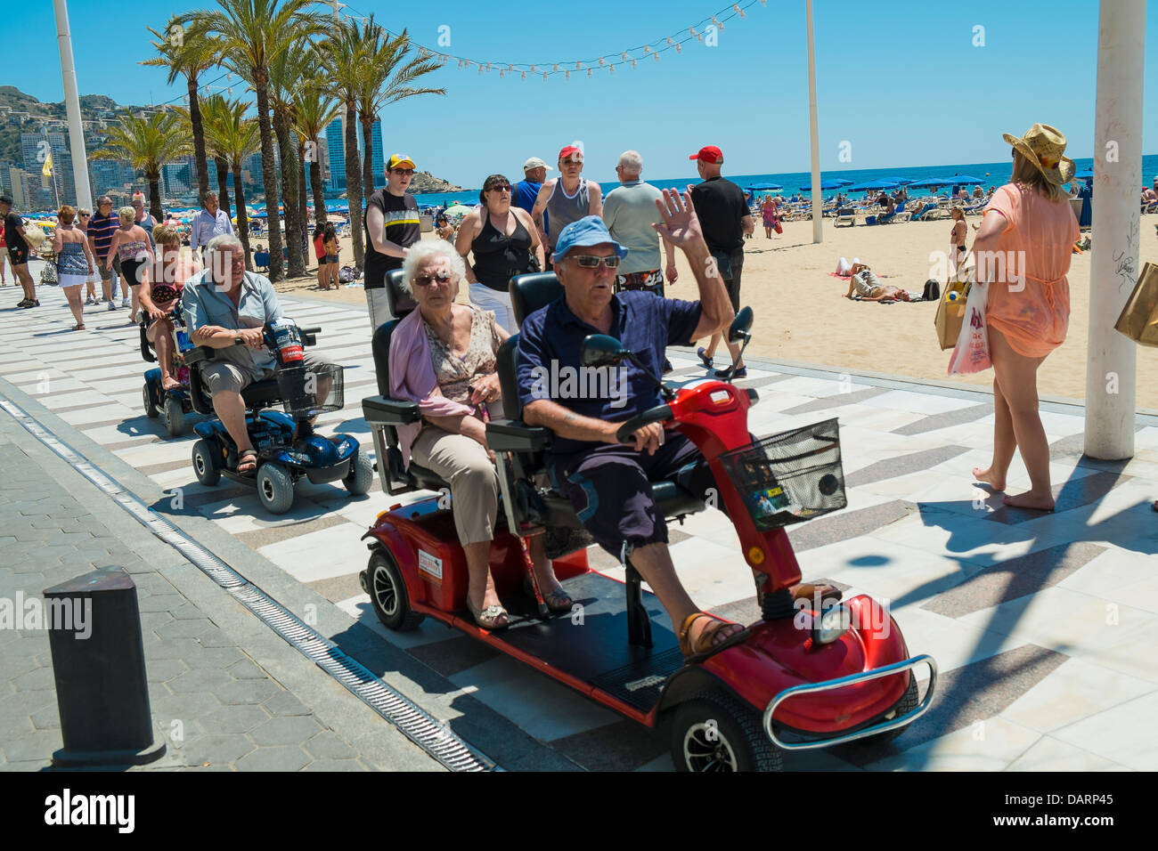 Pensioners riding along mobility scooters on the promenade in Benidorm,Spain Stock Photo
