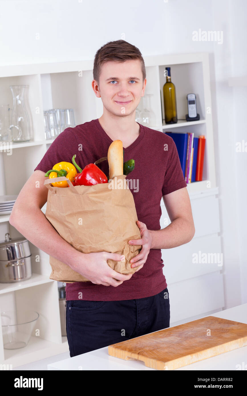 Young man with shopping bag in the kitchen at home Stock Photo