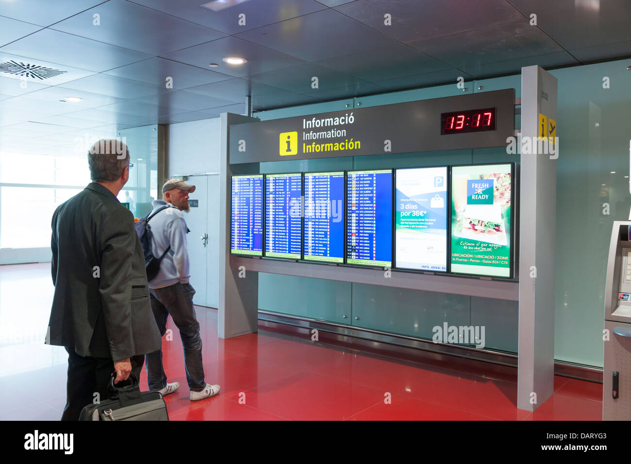 Passengers reading the departures information board at Barcelona Airport Stock Photo