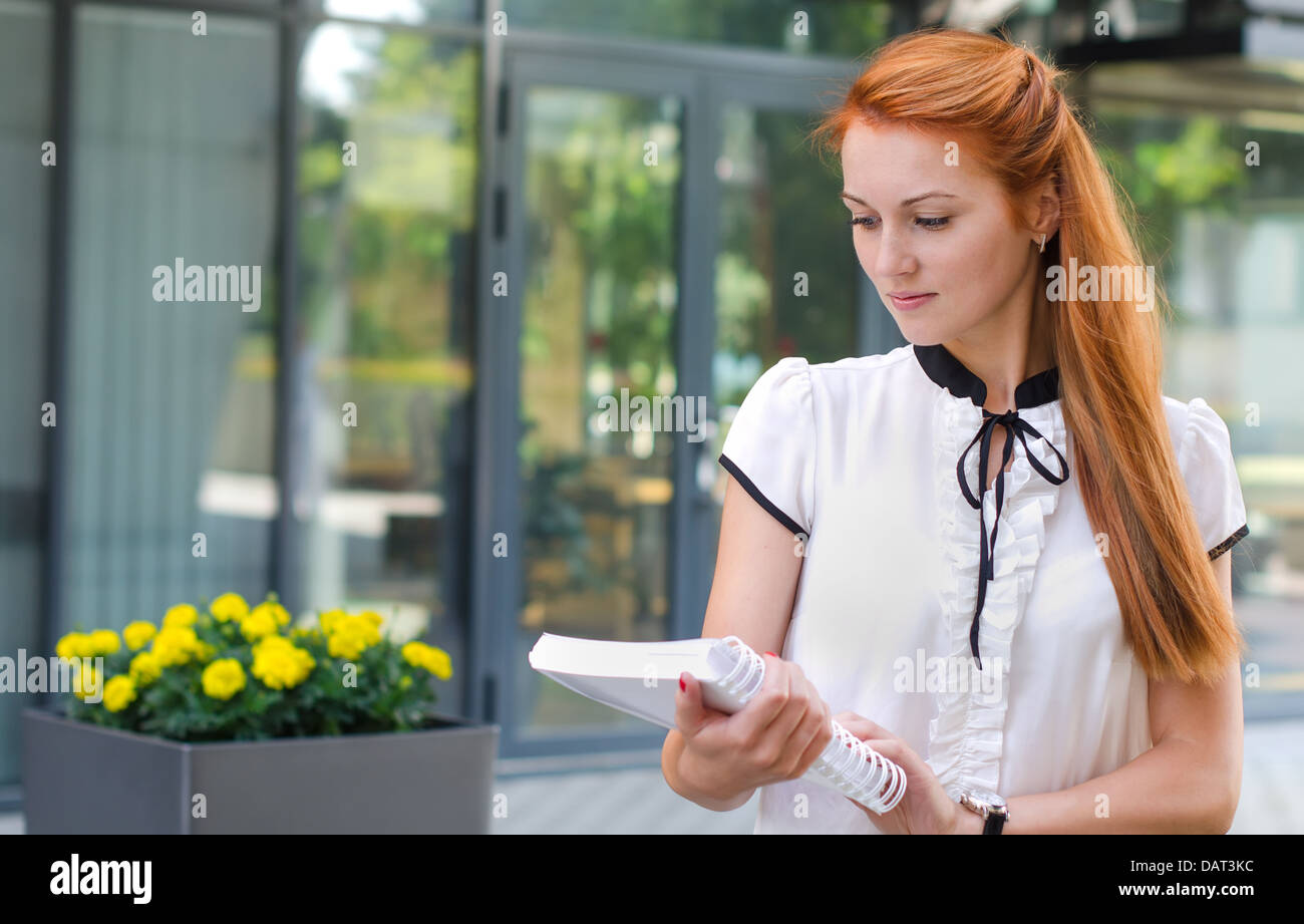 Female student walking outdoors with book Stock Photo - Alamy