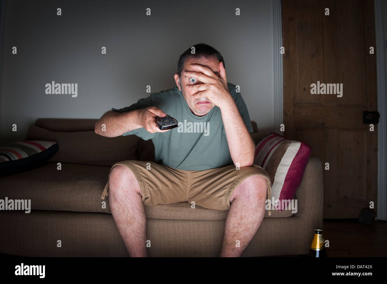 man covering his eyes watching tv or television Stock Photo