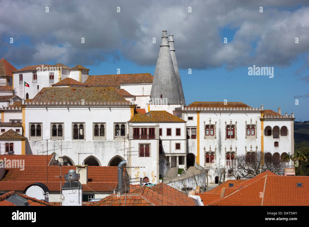 The distinctive conical twin chimneys of Sintra National Palace dominating the skyline of Sintra, Portugal, with traditional houses below.