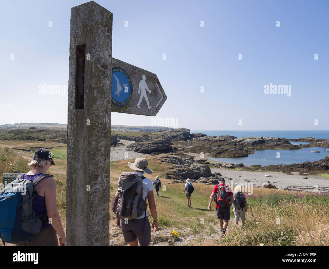 Ramblers walking by public footpath signpost on Isle of Anglesey Coastal Path at Porth-y-Garan Trearddur Holy Island Anglesey North Wales UK Stock Photo