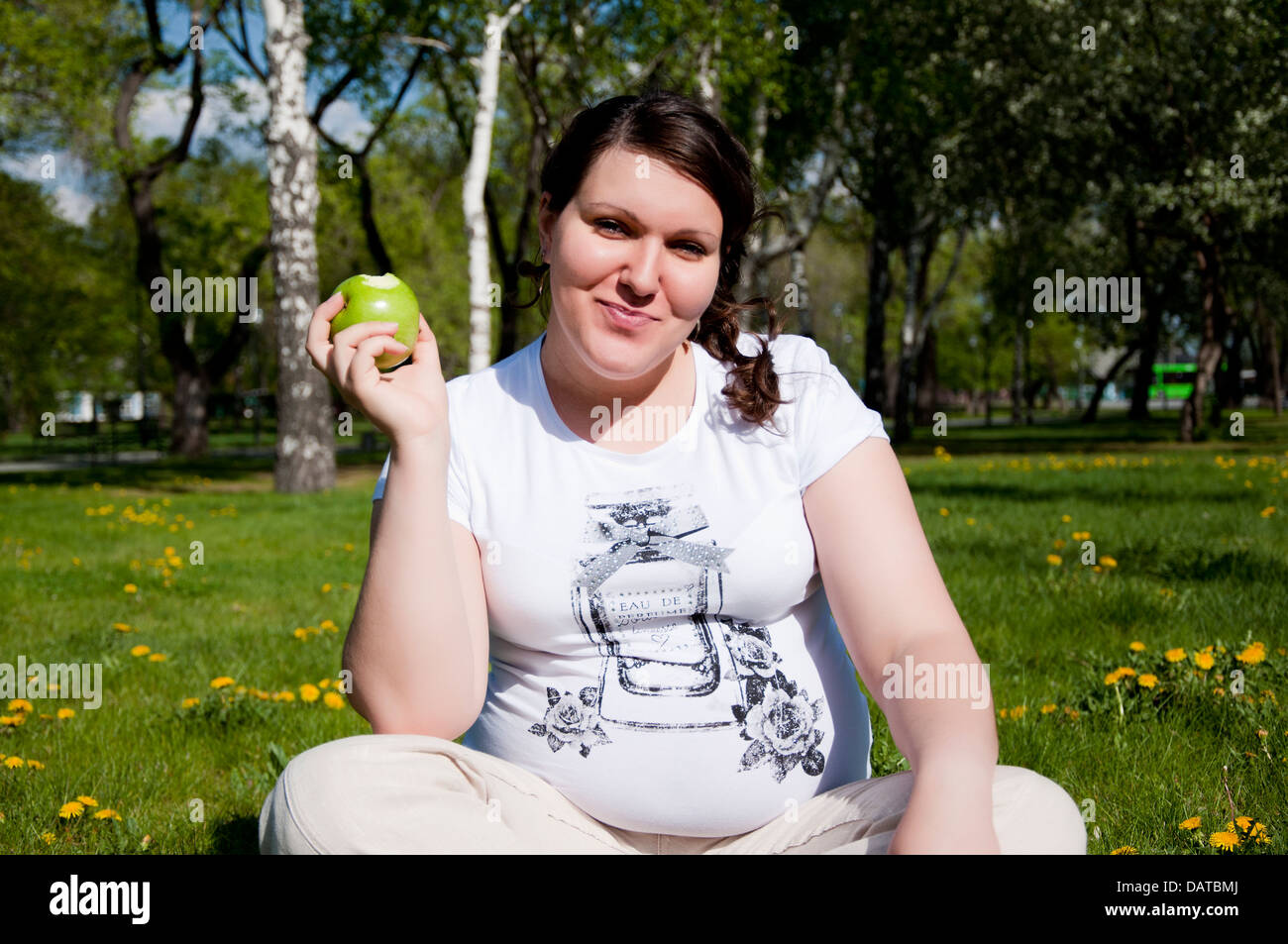 woman sitting on the grass iwith an apple Stock Photo - Alamy