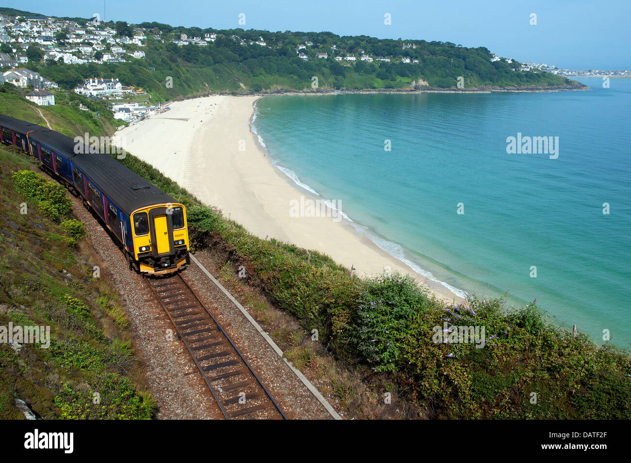 A passenger train passes the beach at carbis bay near st.ives in Stock