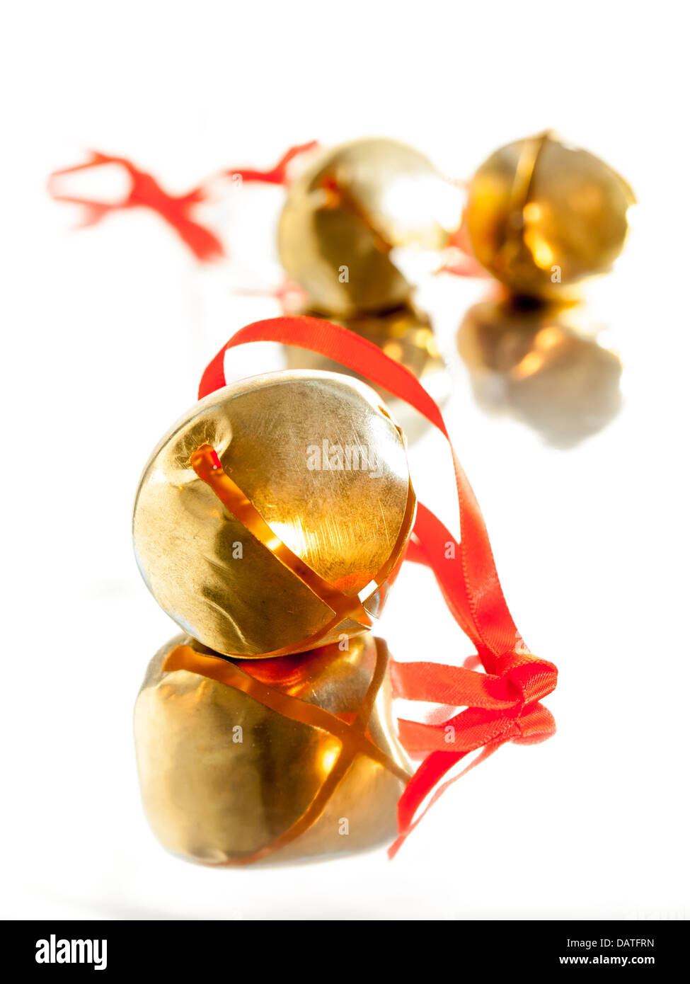 shiny golden sleigh bell with red ribbon tie on reflective surface with