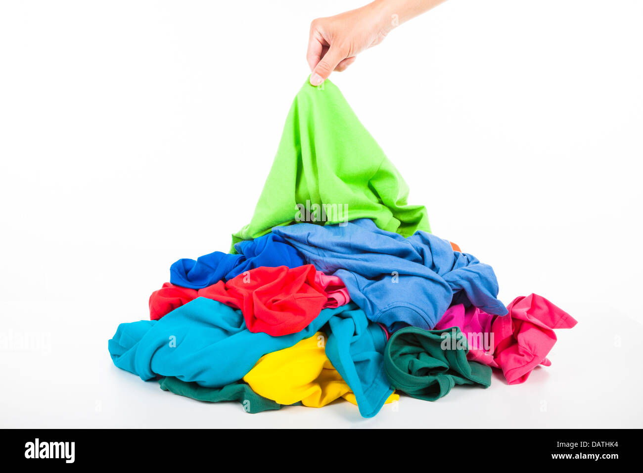 hand pick up a shirt in pile of colorful clothes Stock Photo