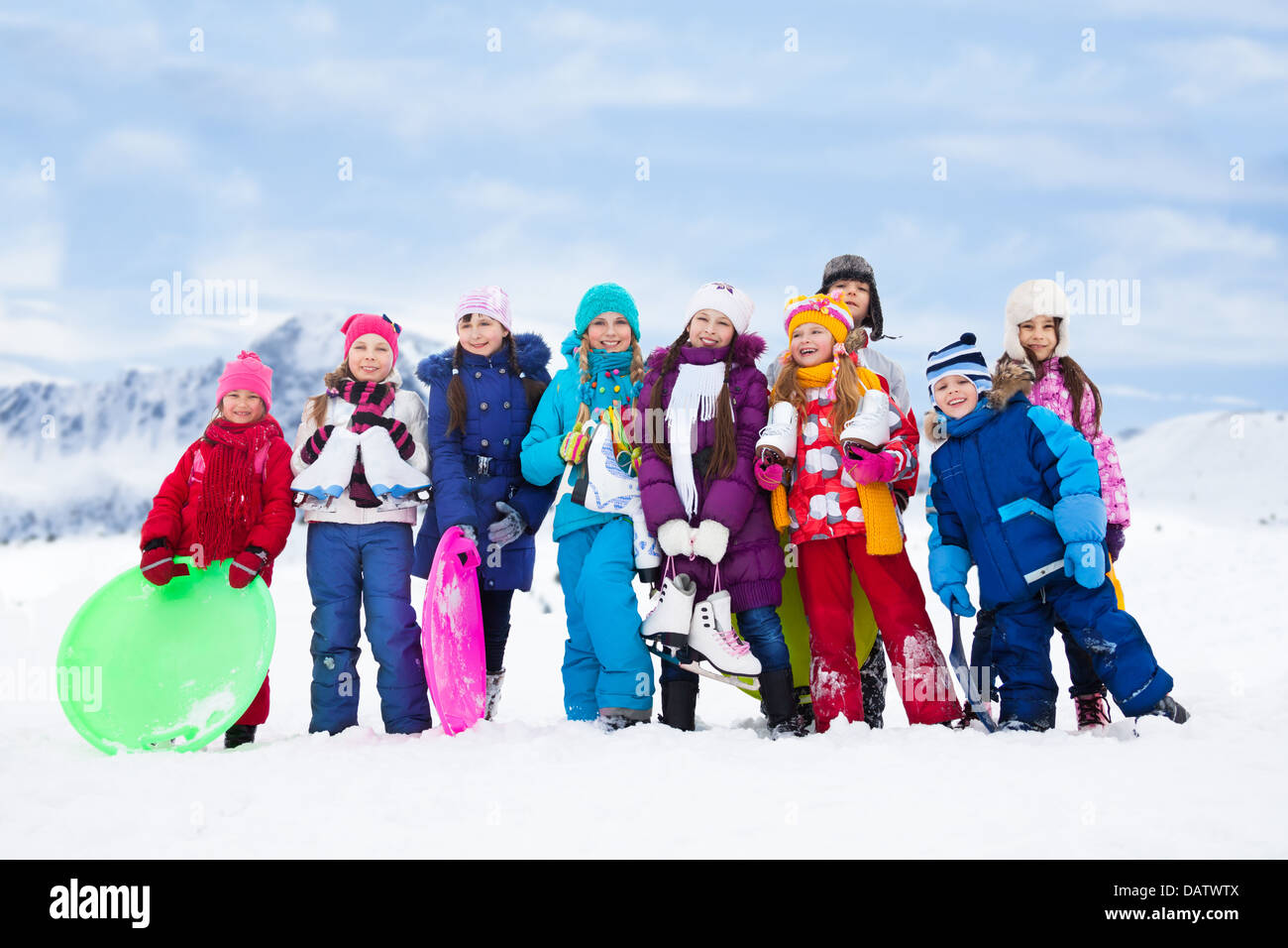 Group of kids together outside in snow with sled, ice skates having fun ...