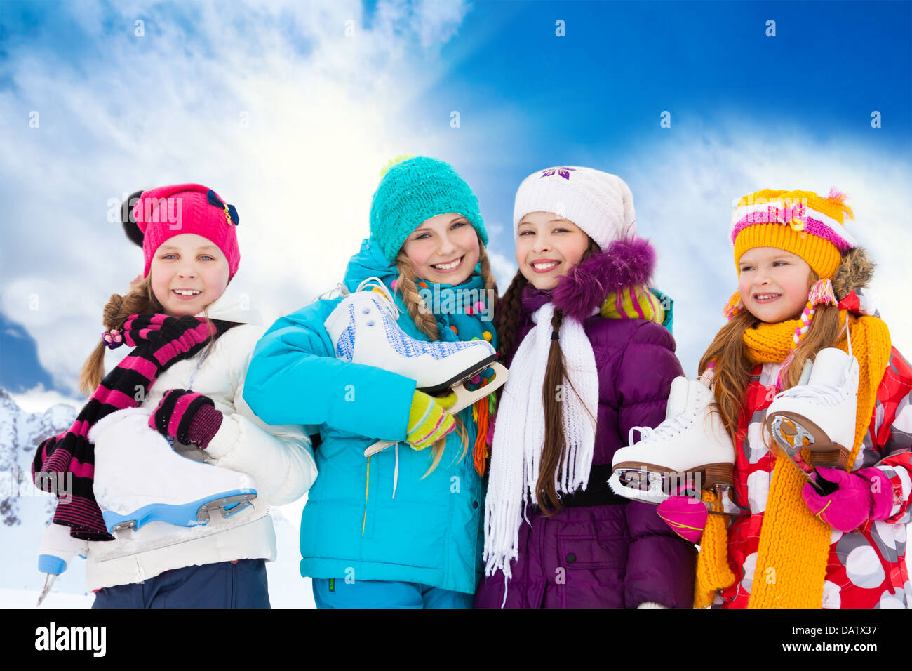 Close portrait of group of four happy smiling Caucasian girls friends standing outside with ice-skates Stock Photo