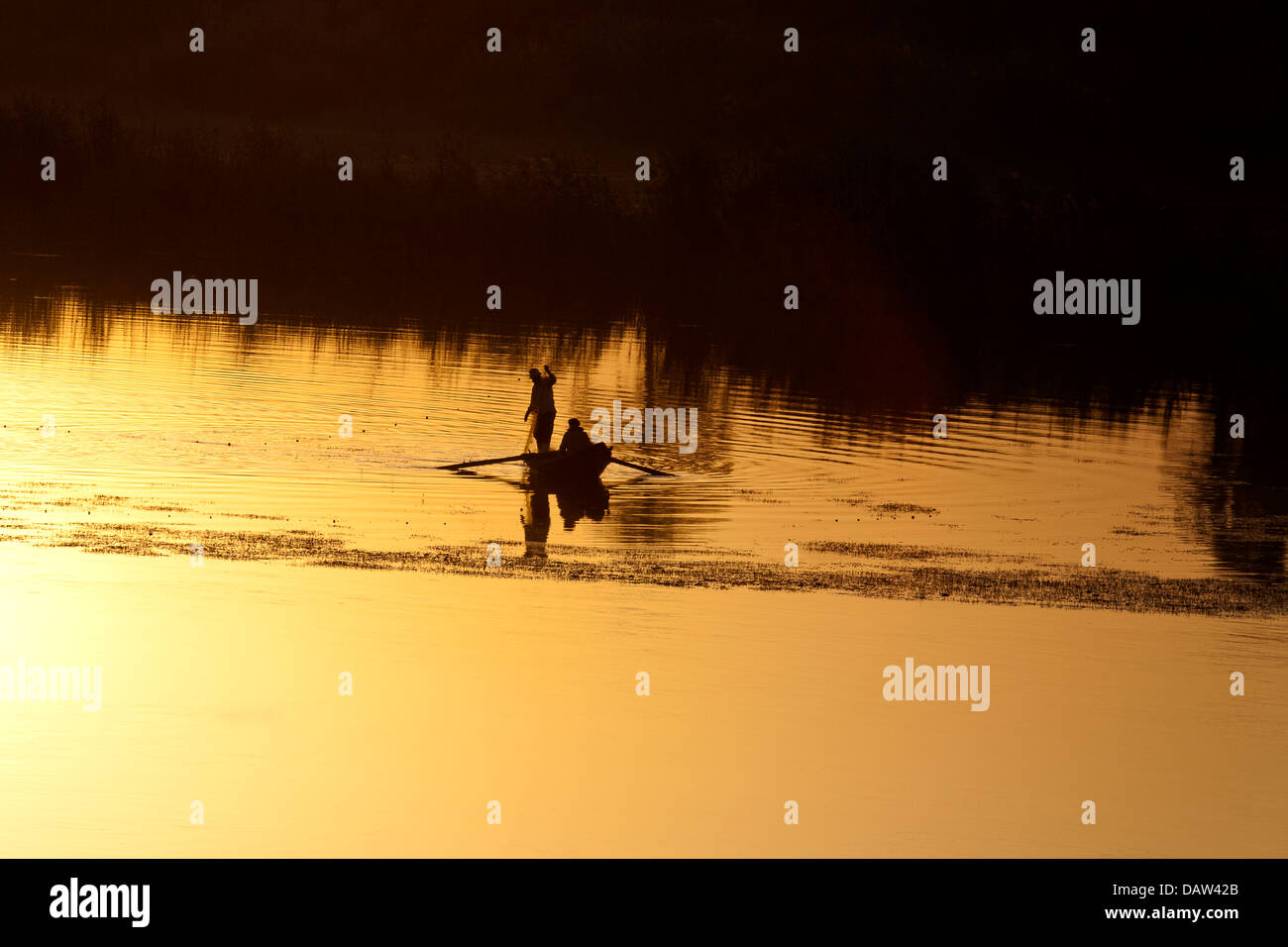 Two Nile fishermen silhouetted against golden reflection at sunset on the river Nile Egypt Africa Stock Photo