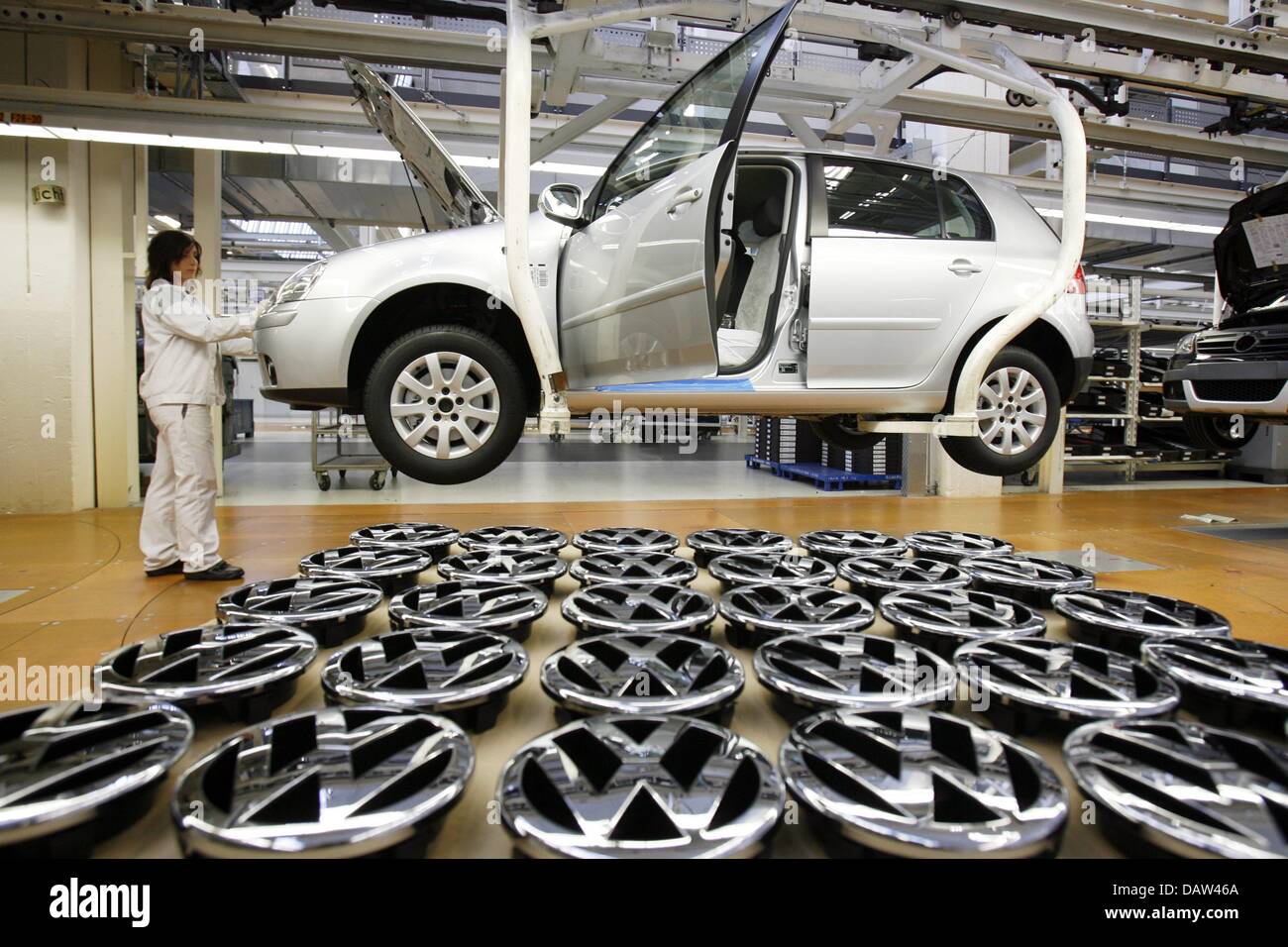 A worker attaches VW logos on a brand new Golf 5 at the Volkswagen plant in Wolfsburg, Thursday 15 February 2007. Photo: Jochen Luebke Stock Photo