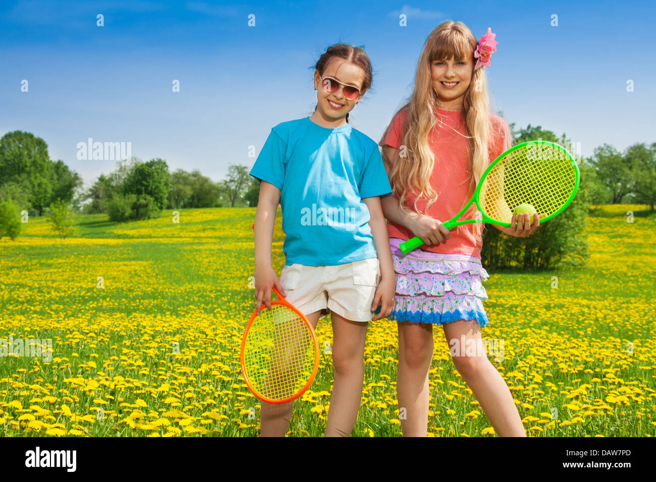 Two beautiful girls with tennis racquets standing in the park Stock