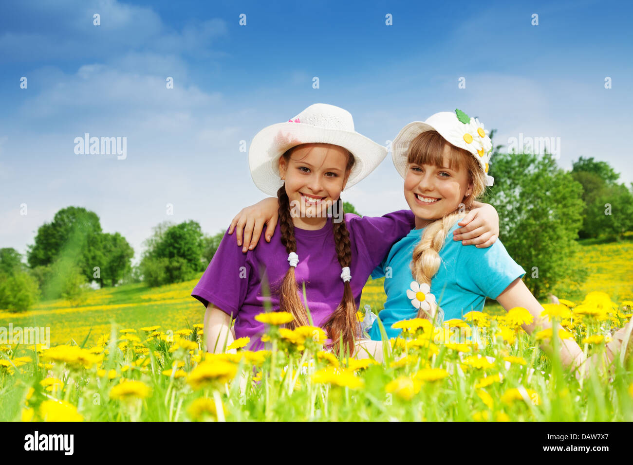 Two smiling happy girls in summer hats sitting in dandelion field Stock ...